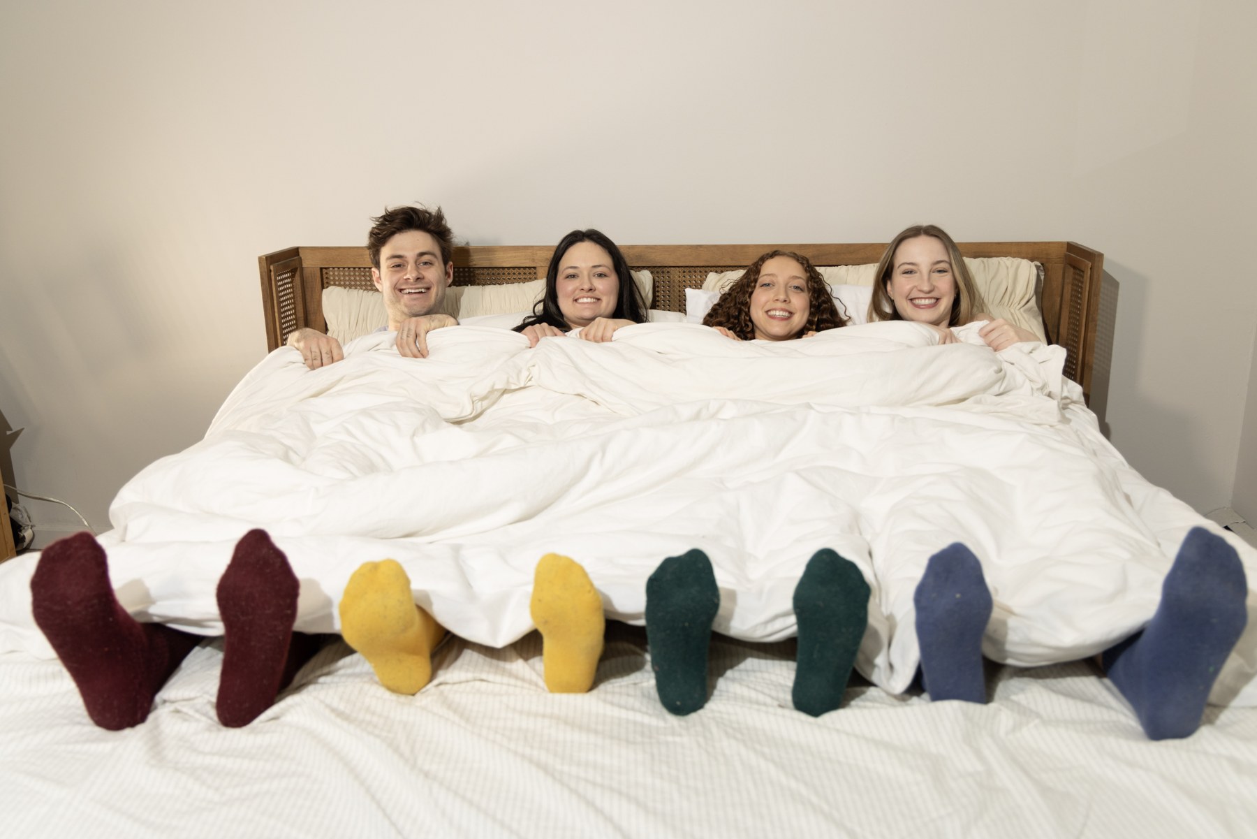 The four tucked into one bed, four pairs of socks in four colors sticking out