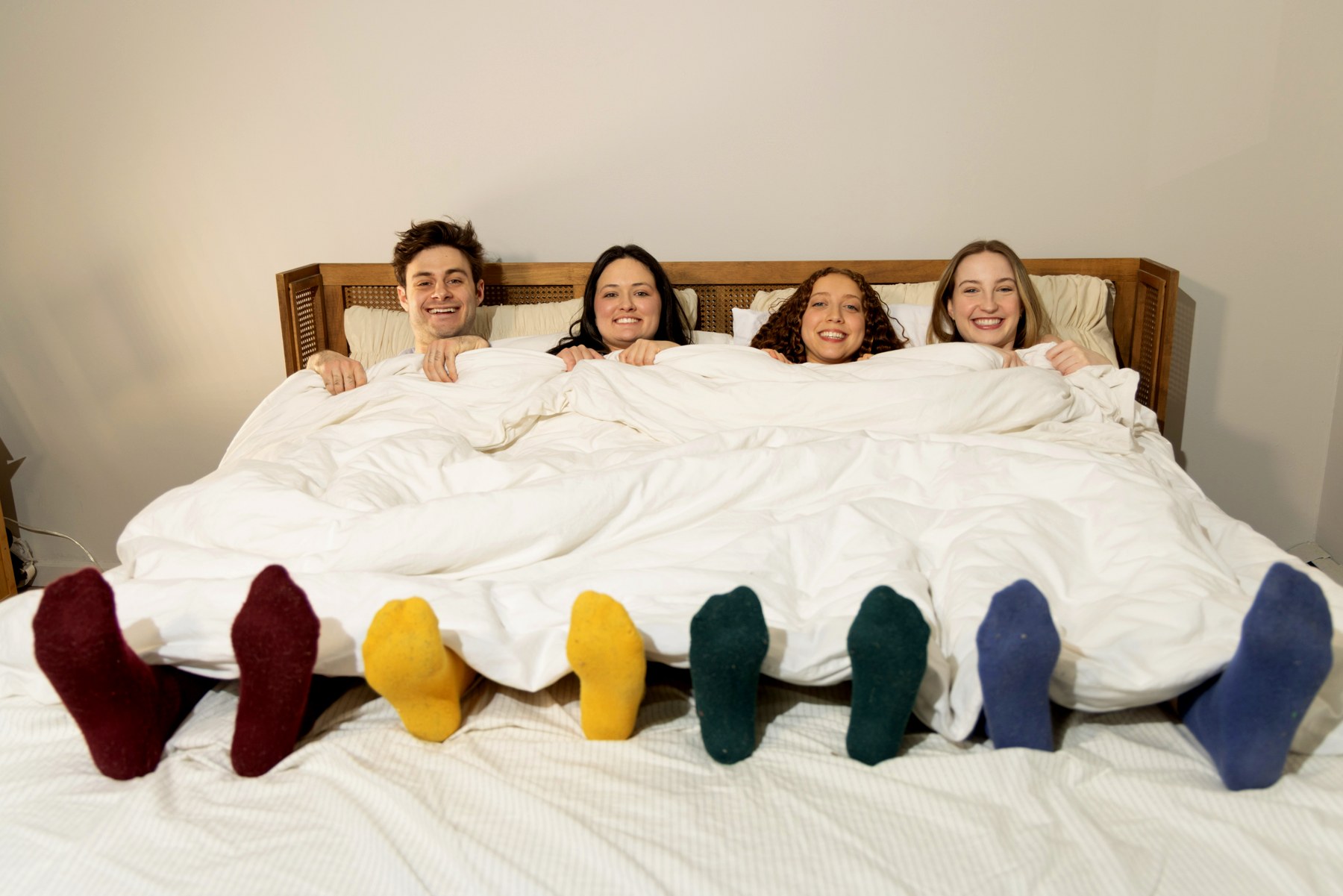 The four tucked into one bed, four pairs of socks in four colors sticking out